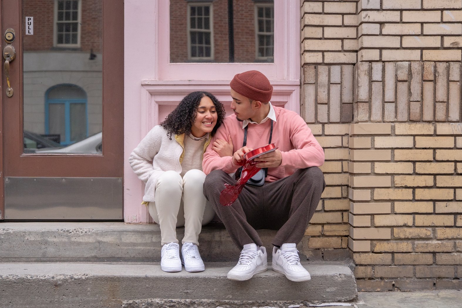 Happy ethnic woman cuddling with boyfriend presenting gift box on Saint Valentines Day